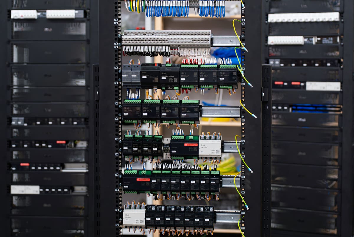 Rows of controllers and gateways on DIN rails inside an automation cabinet
